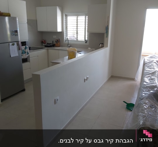 מטבח עם קיר גבס לבן ומטאטא ירוק על הרצפה